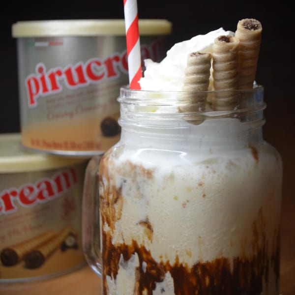 Venezuelan Pirucream milkshake with whipped cream, wafer rolls, and a red-striped straw.